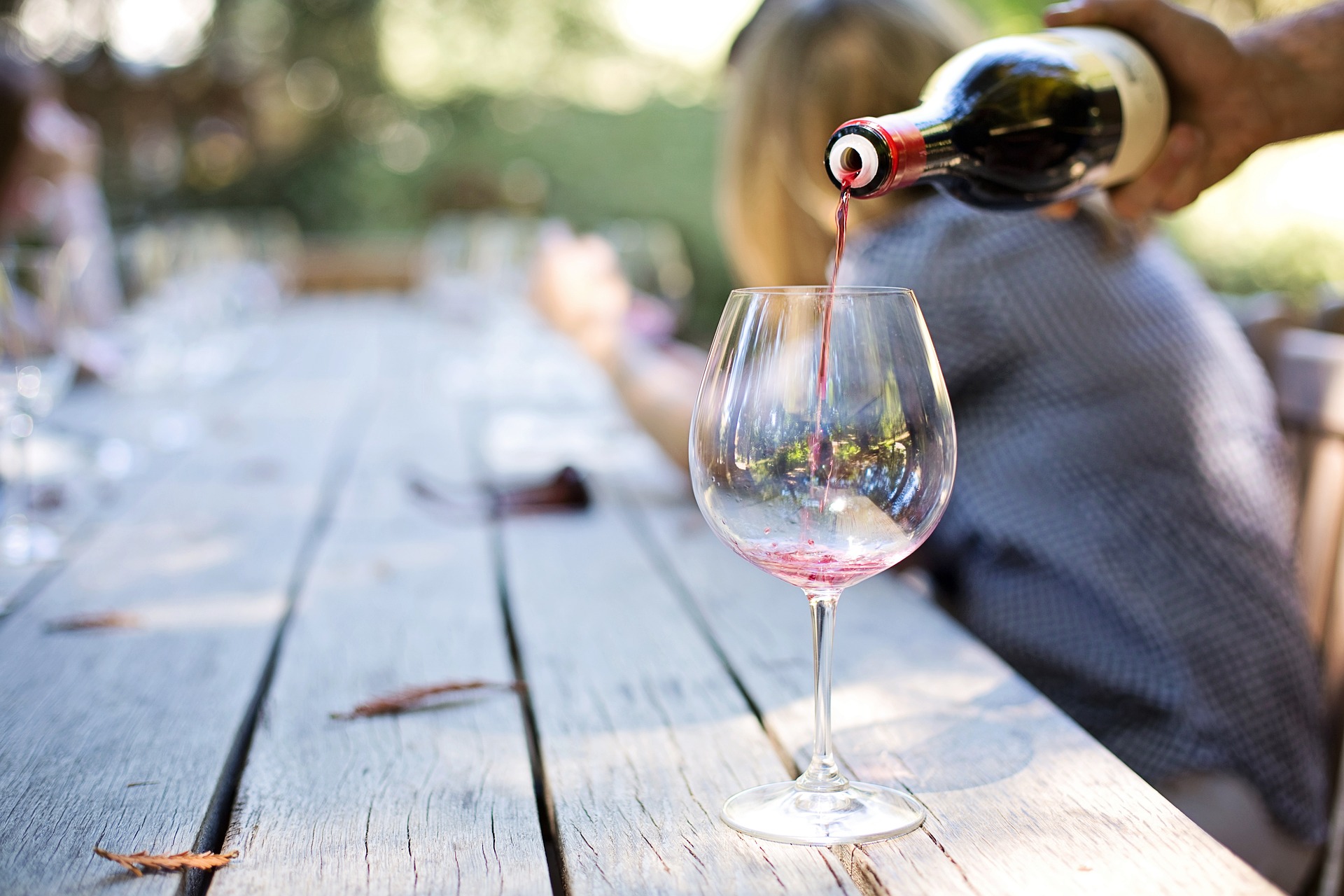 a hand pouring wine into a wine glass