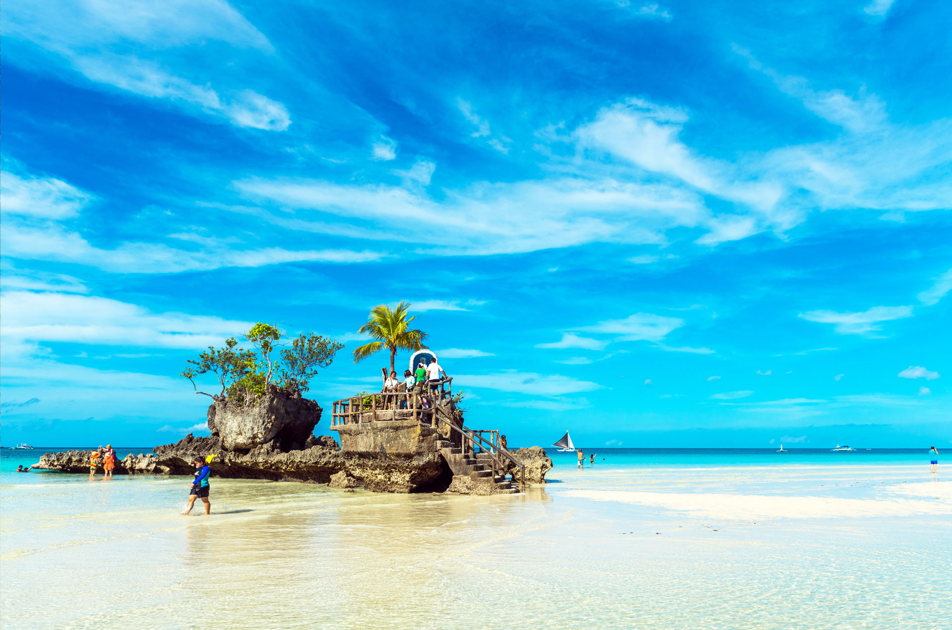 People sitting on the beach shore with palm trees behind them.