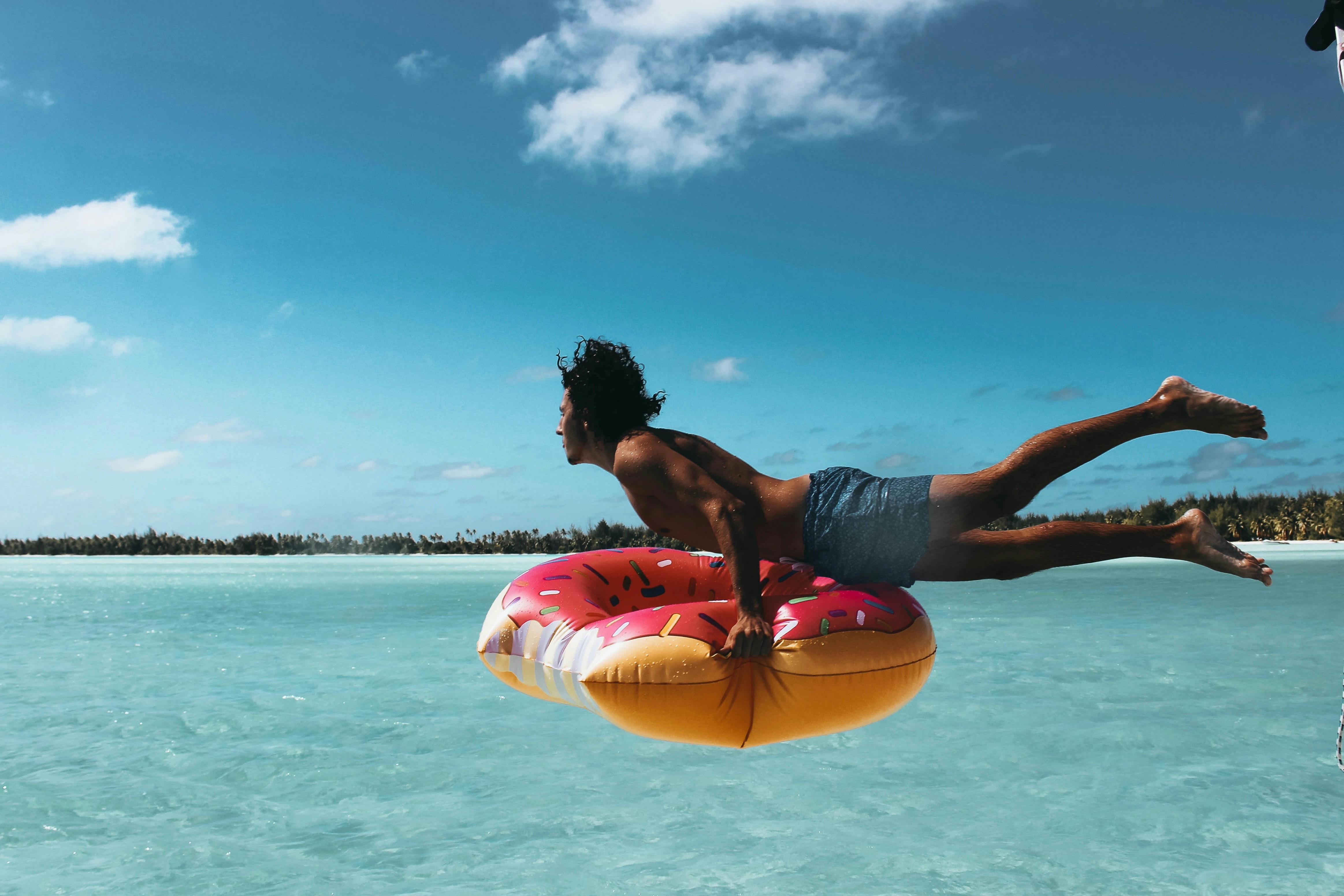 Man with a floater jumping into the ocean