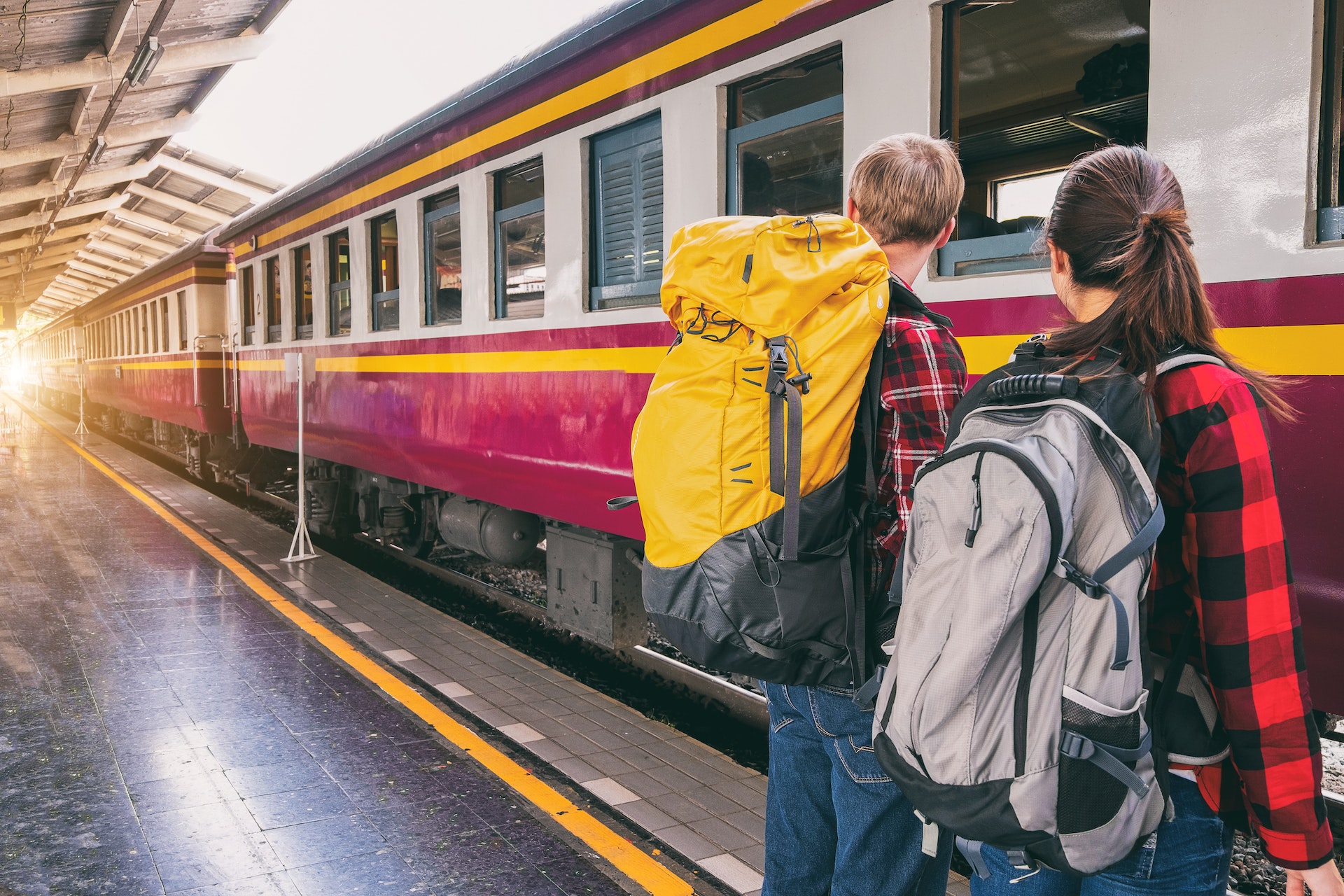 Man and woman with big backpacks waiting for their train.