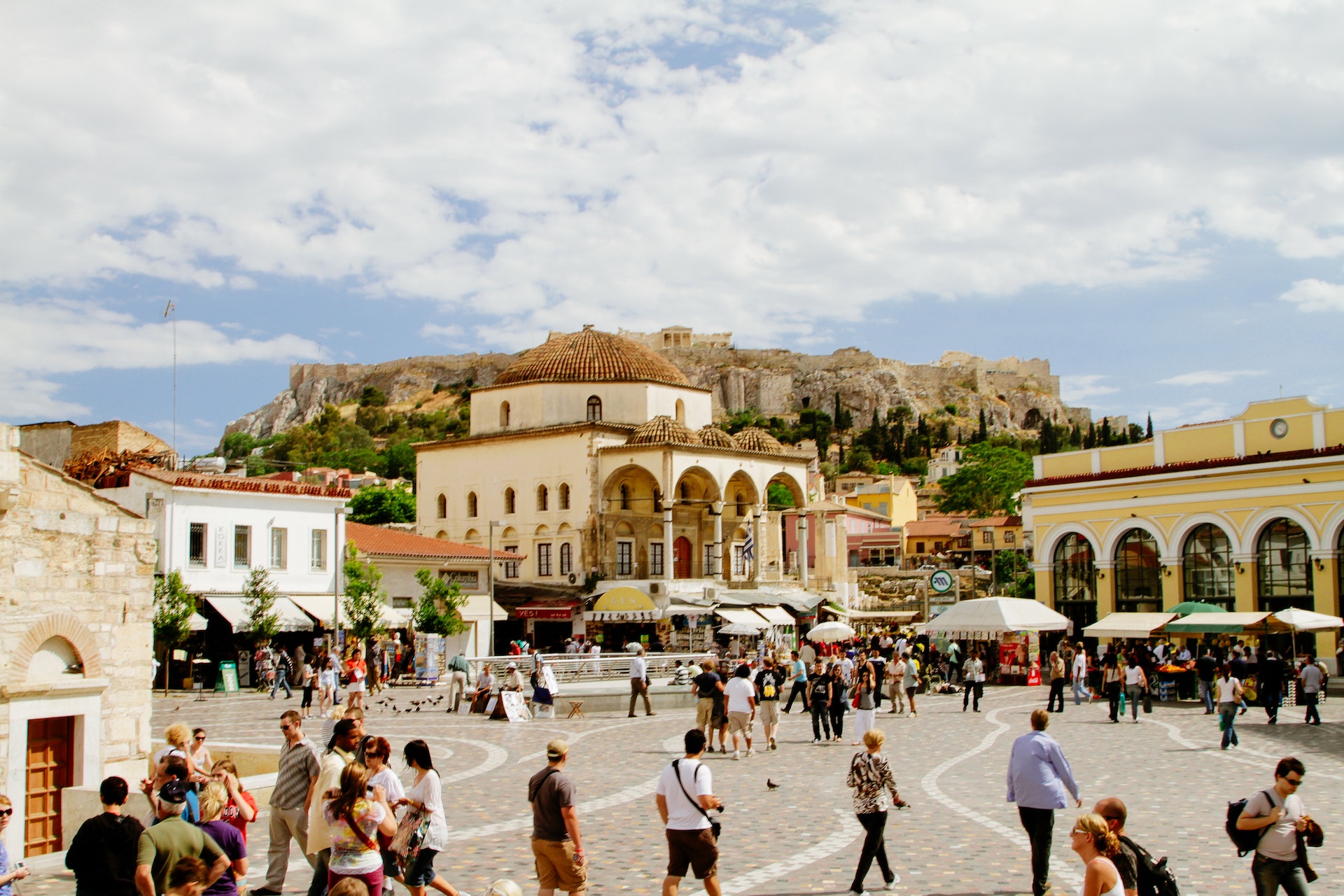  A busy street with tourists, traditional buildings, and a mountain range in the background. 