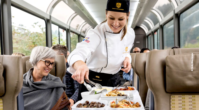 Chef serving lunch seatside in Rocky Mountaineer's SilverLeaf coach