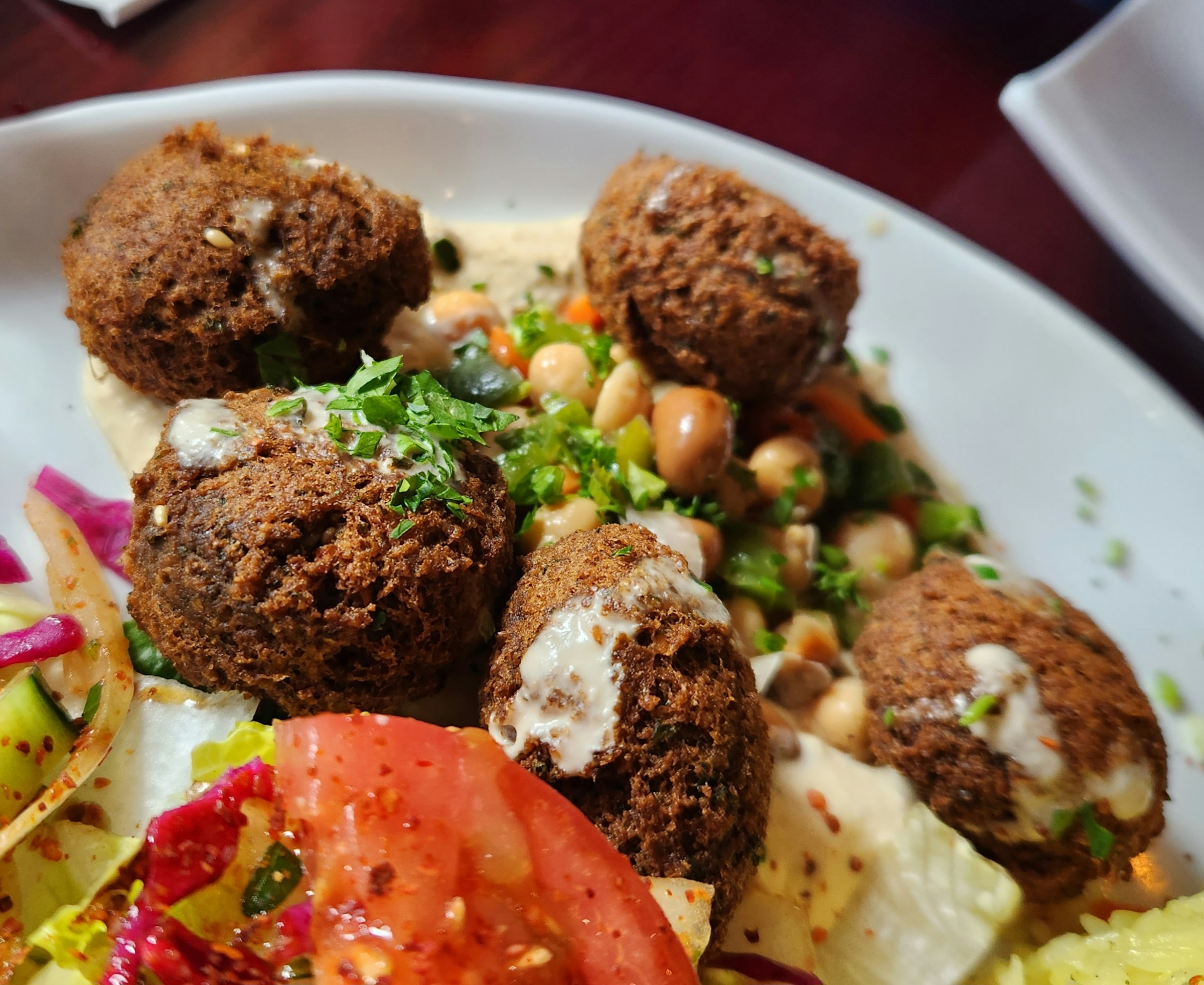 Crispy, fried falafel over a plate of rice and colourful vegetables and spices.