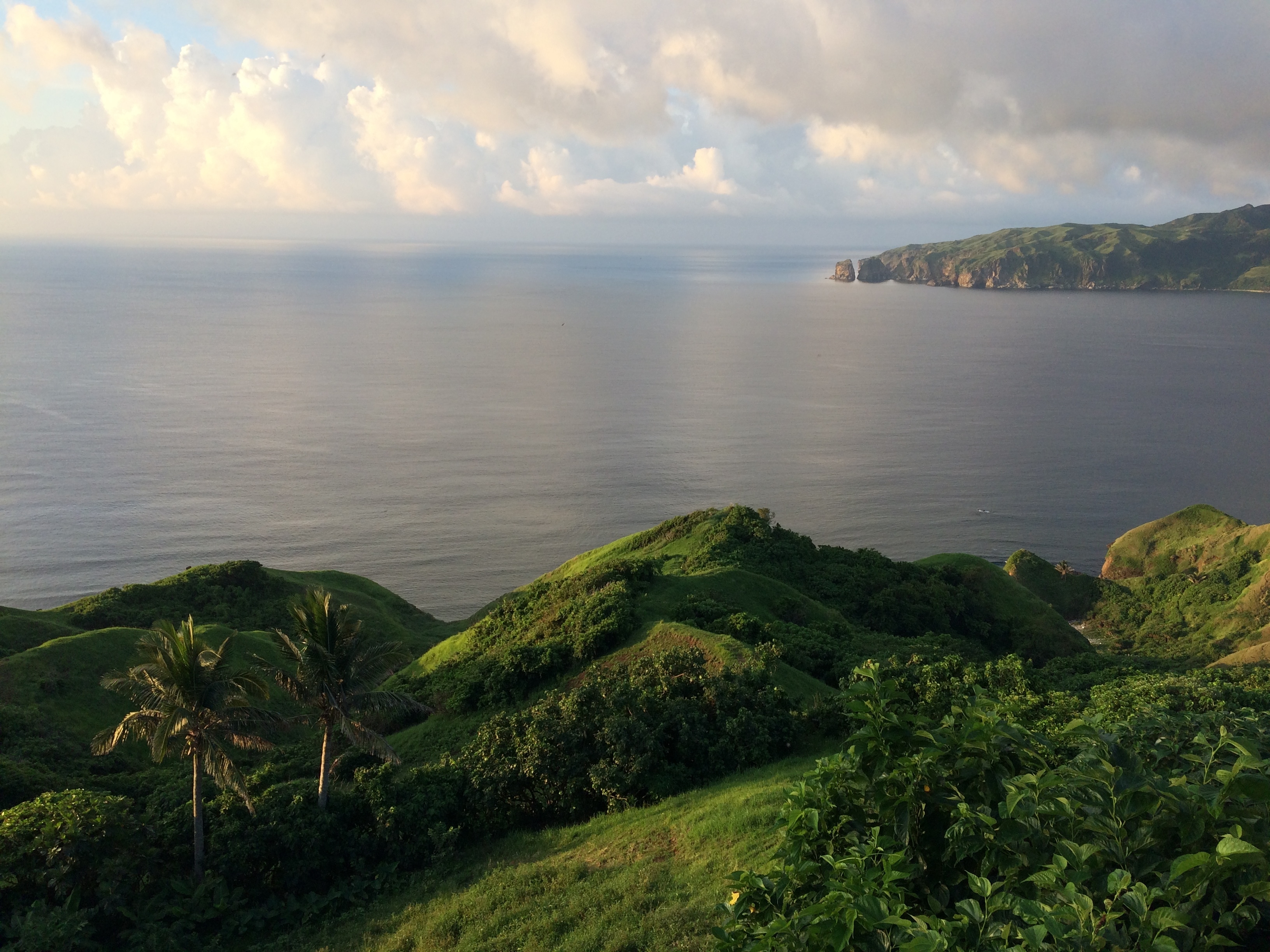 Lush green hills roll down to the turquoise waters of the sea in Rarotonga, Cook Islands