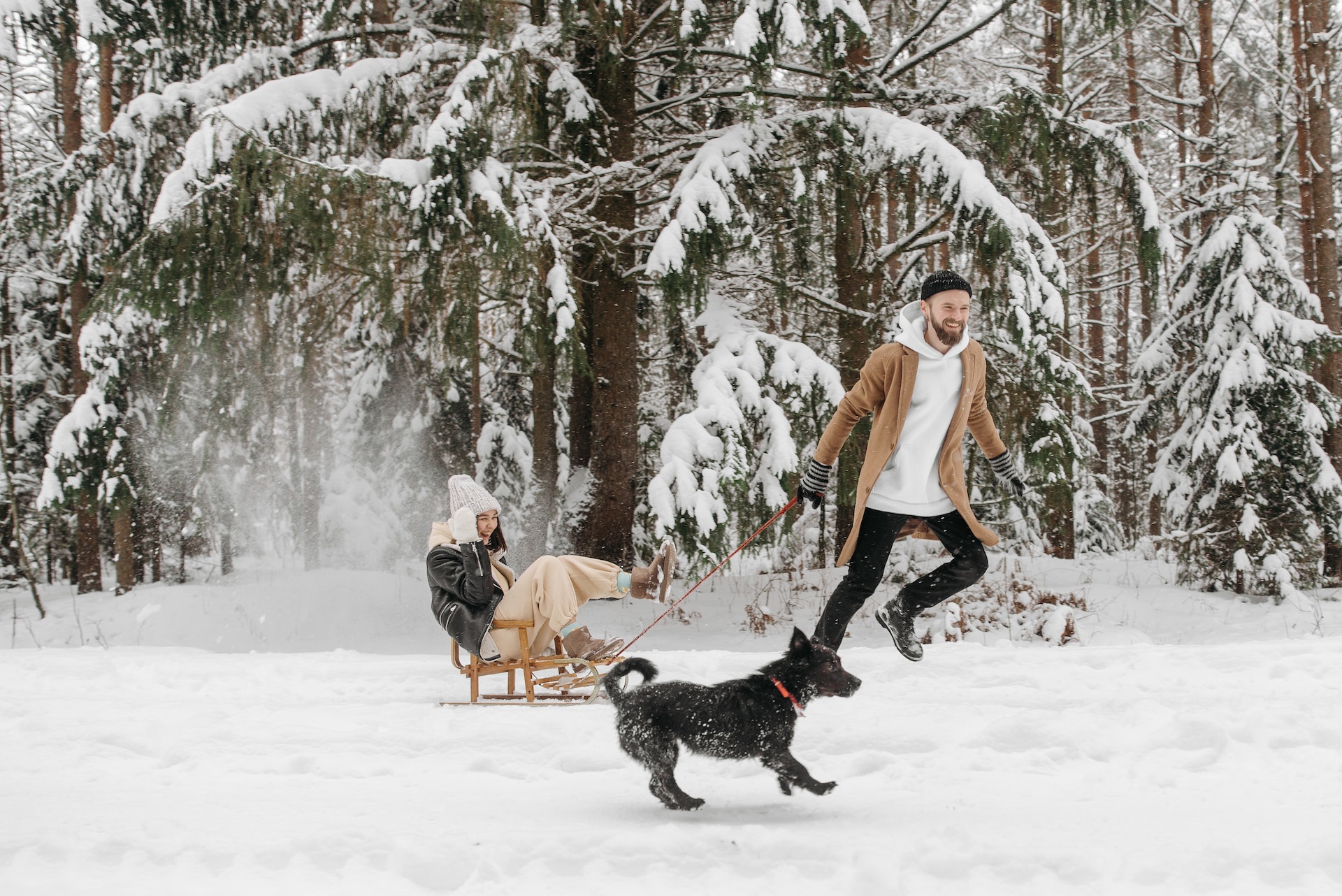 A man pulling a woman on a sleigh in the snow