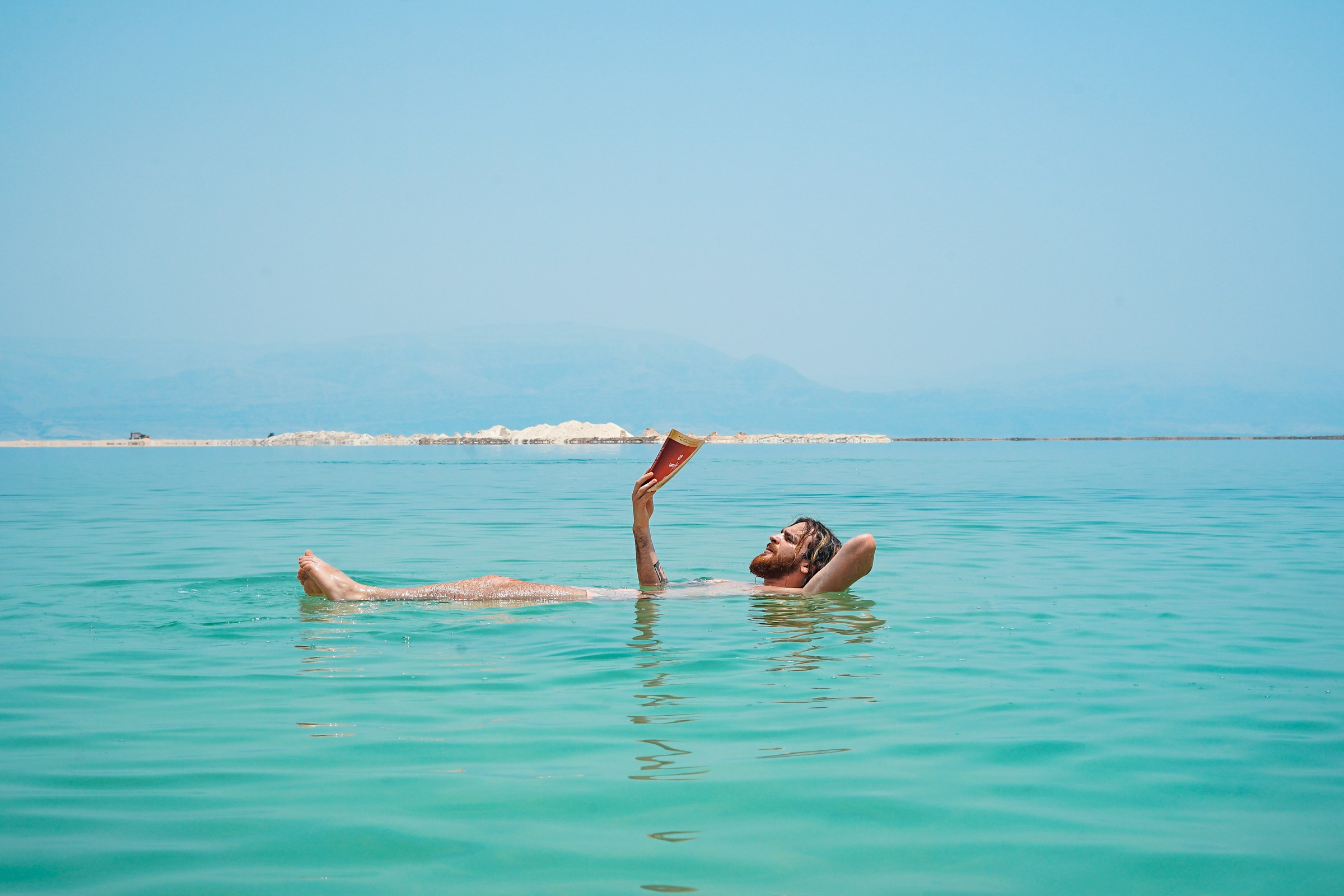 A man relaxing and reading a book while floating in the Dead Sea’s highly saline waters.
