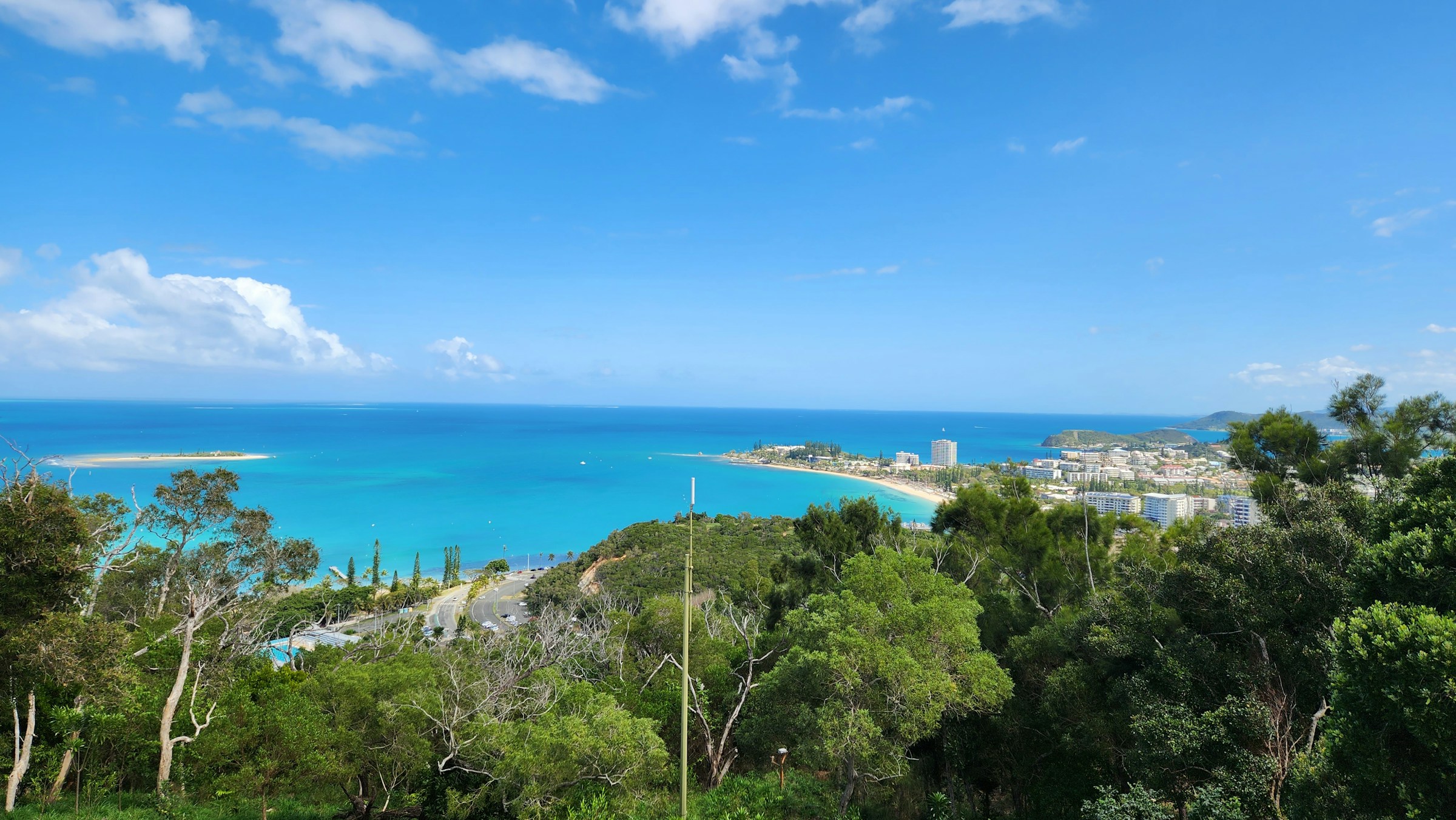 A view of the ocean and sky framed by trees and a city