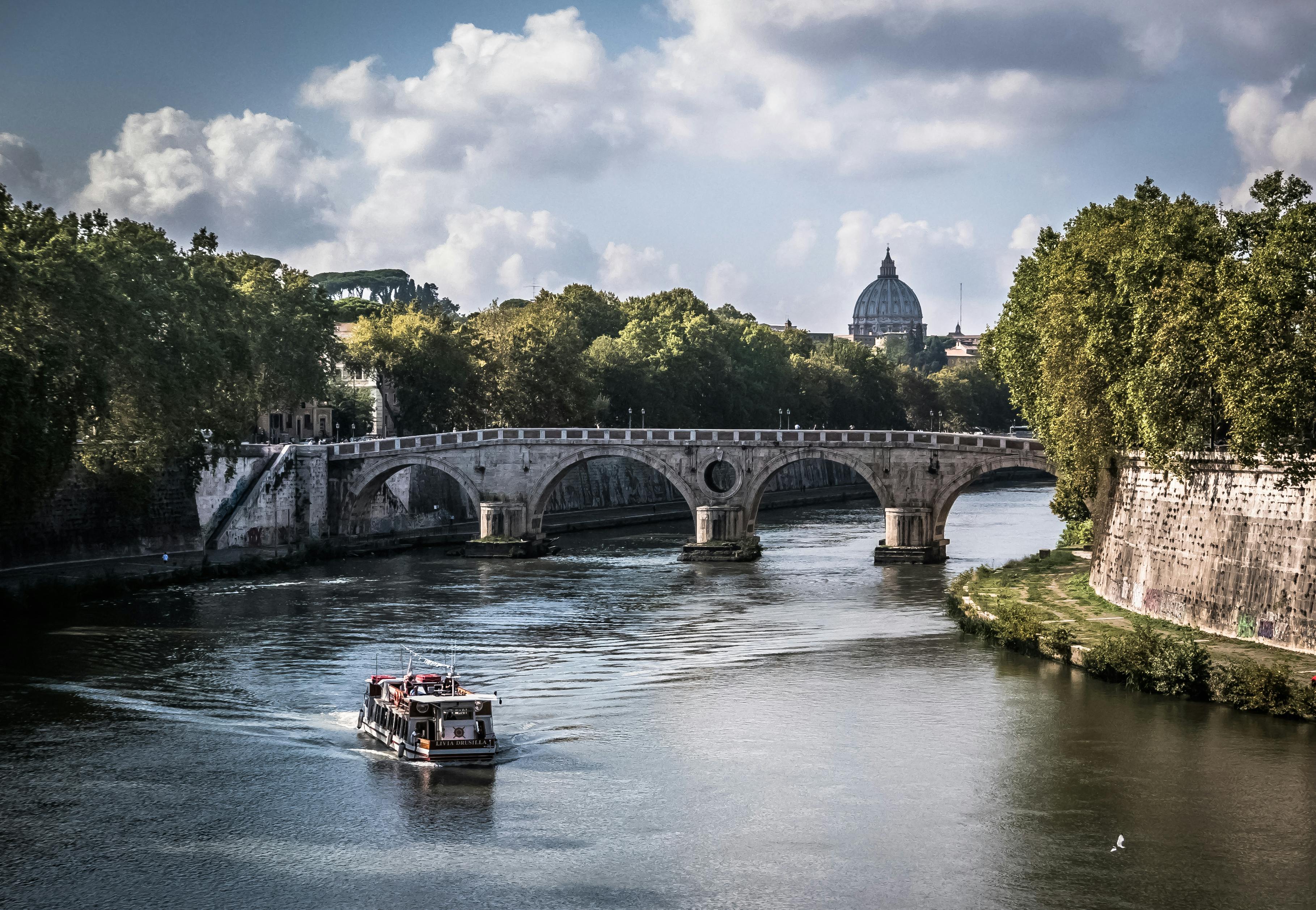 A graceful boat glides beneath a stone bridge, framed by classic European architecture and tranquil waterways.