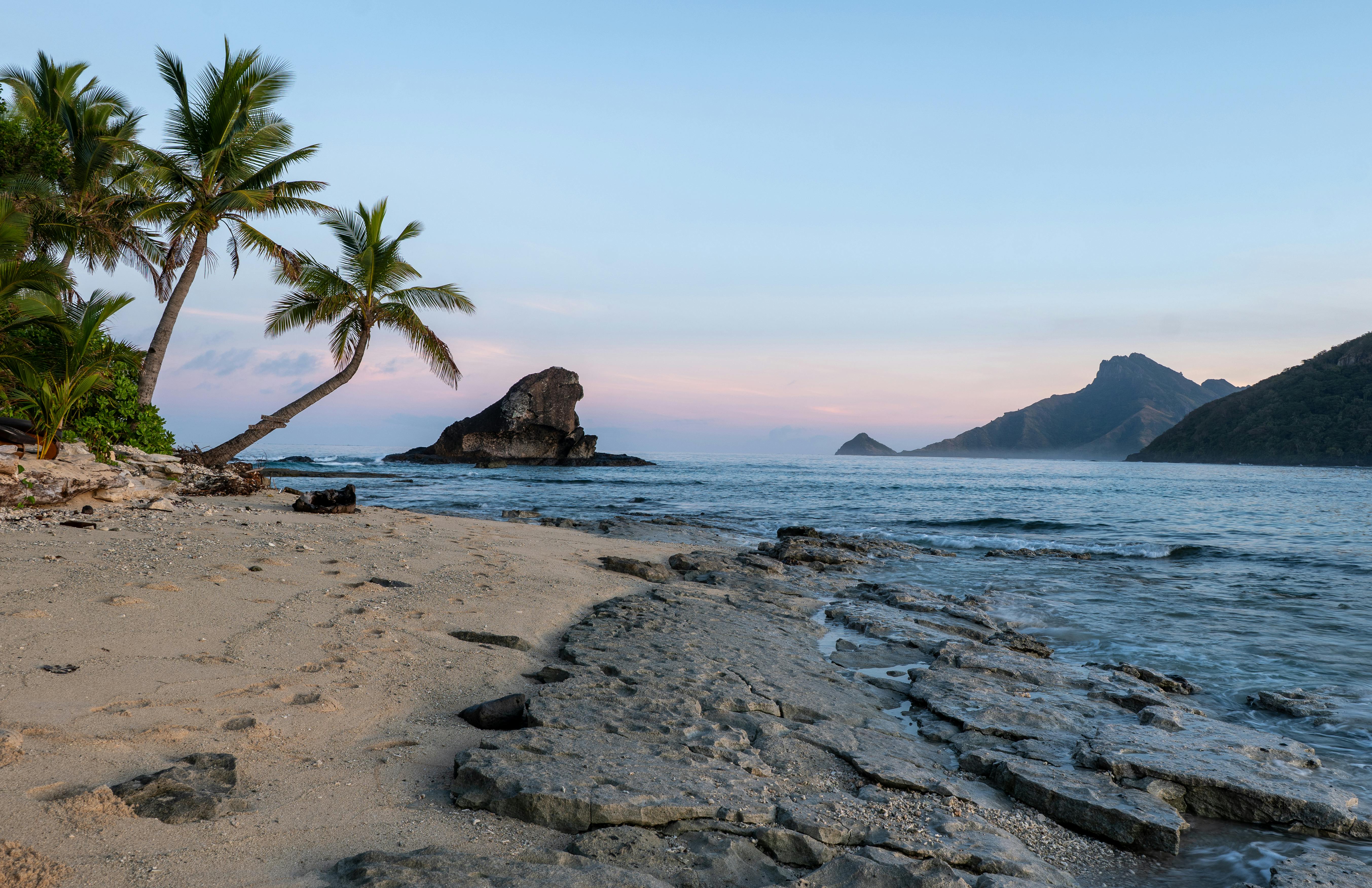 A tranquil sunrise over a palm-fringed beach in Fiji
