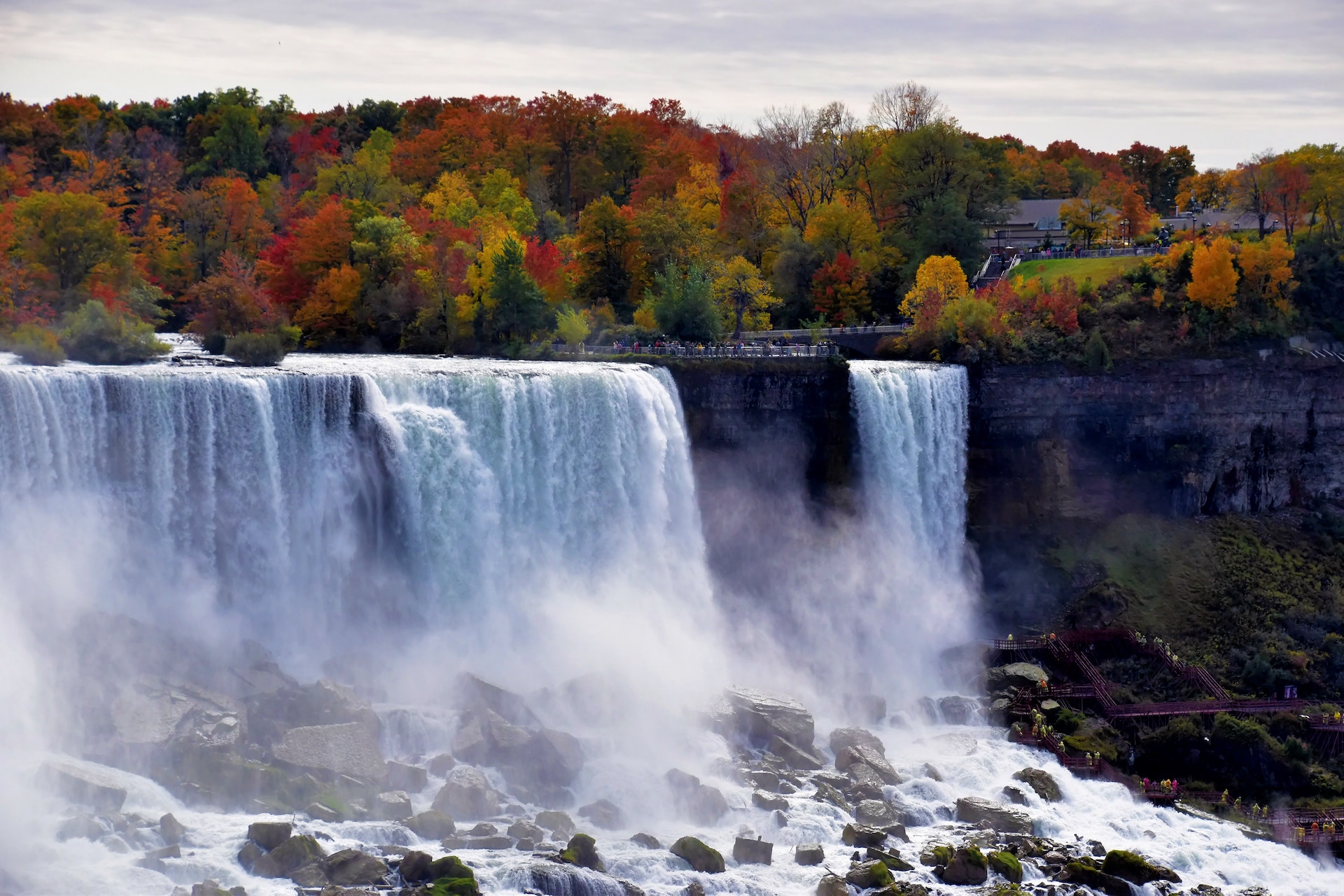 The iconic Niagara Falls with red and orange autumn foliage.