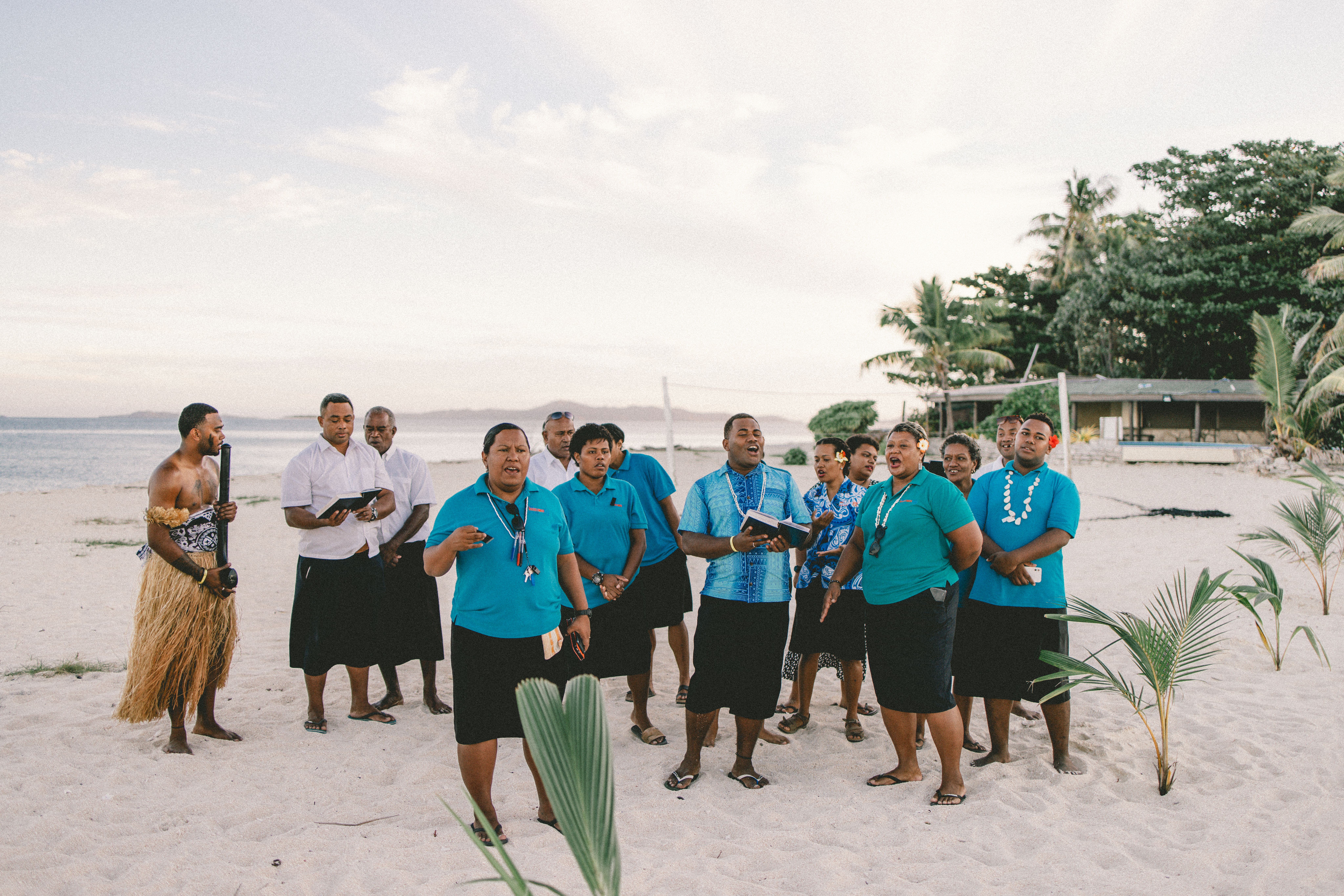 A group of Fijian performers sing and play traditional music on a tropical beach at Beachcomber Island