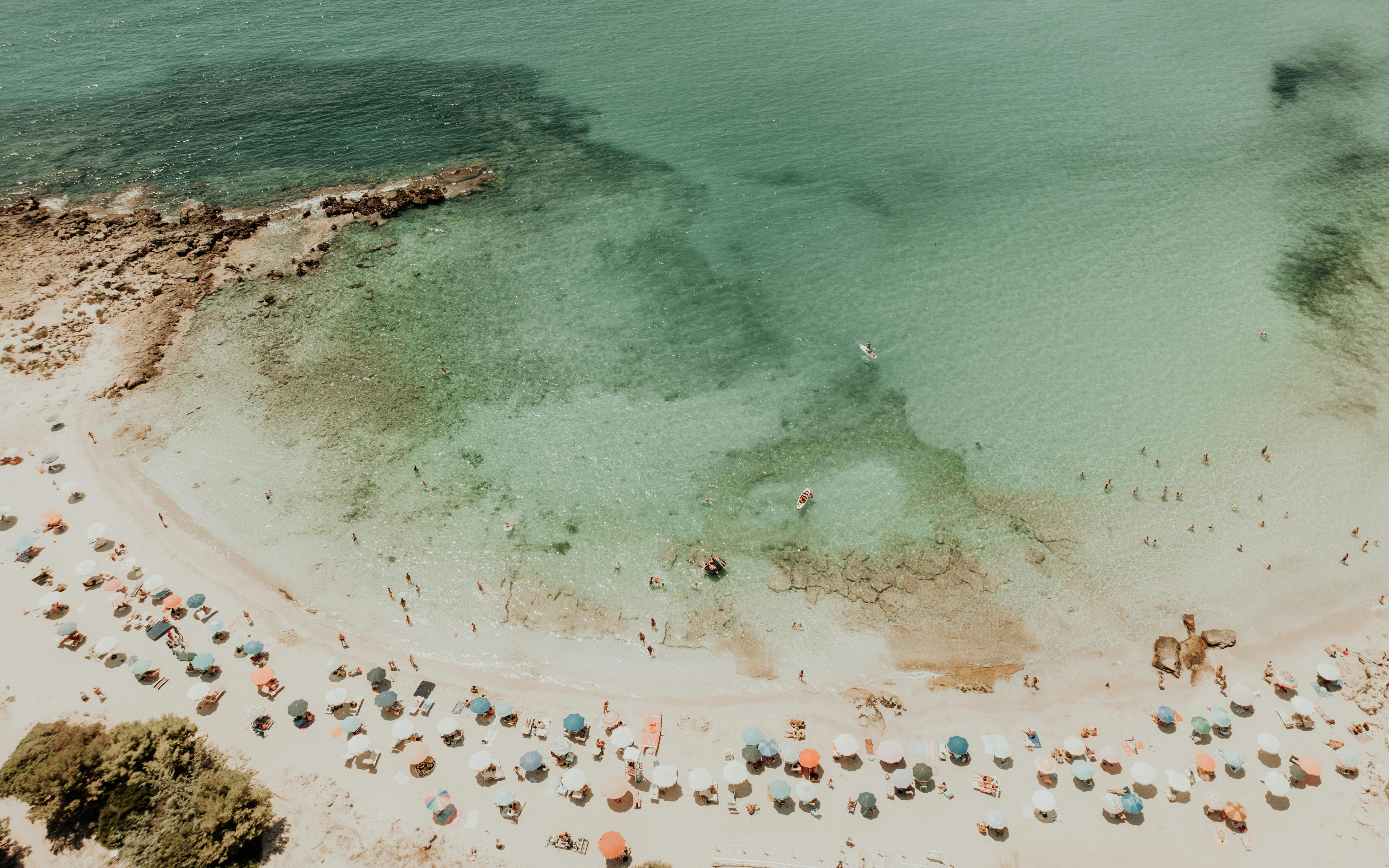 Rows of beach umbrellas line a sun-drenched shore in southern Italy