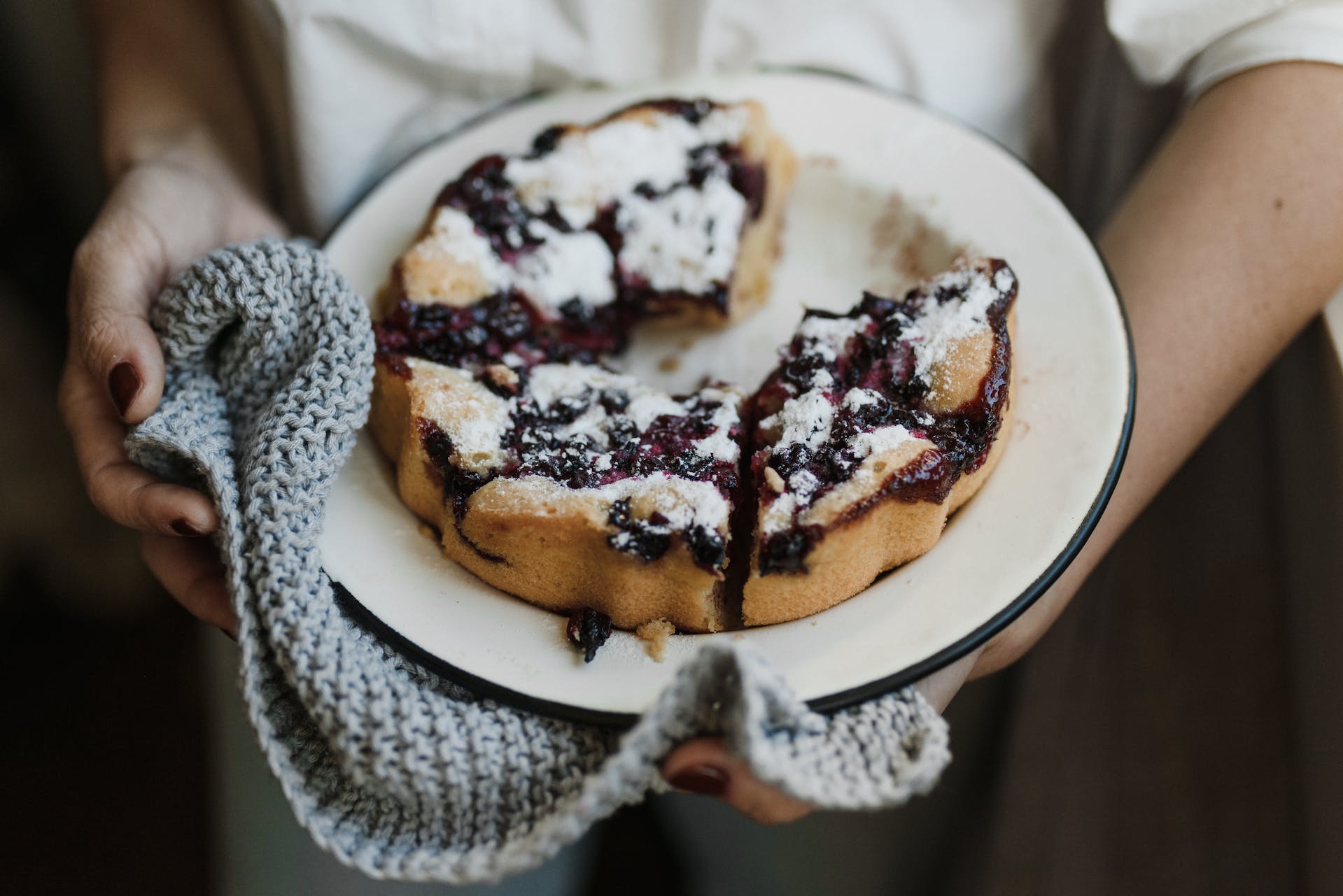 A person holding a plate of freshly baked mustikkapiirakka