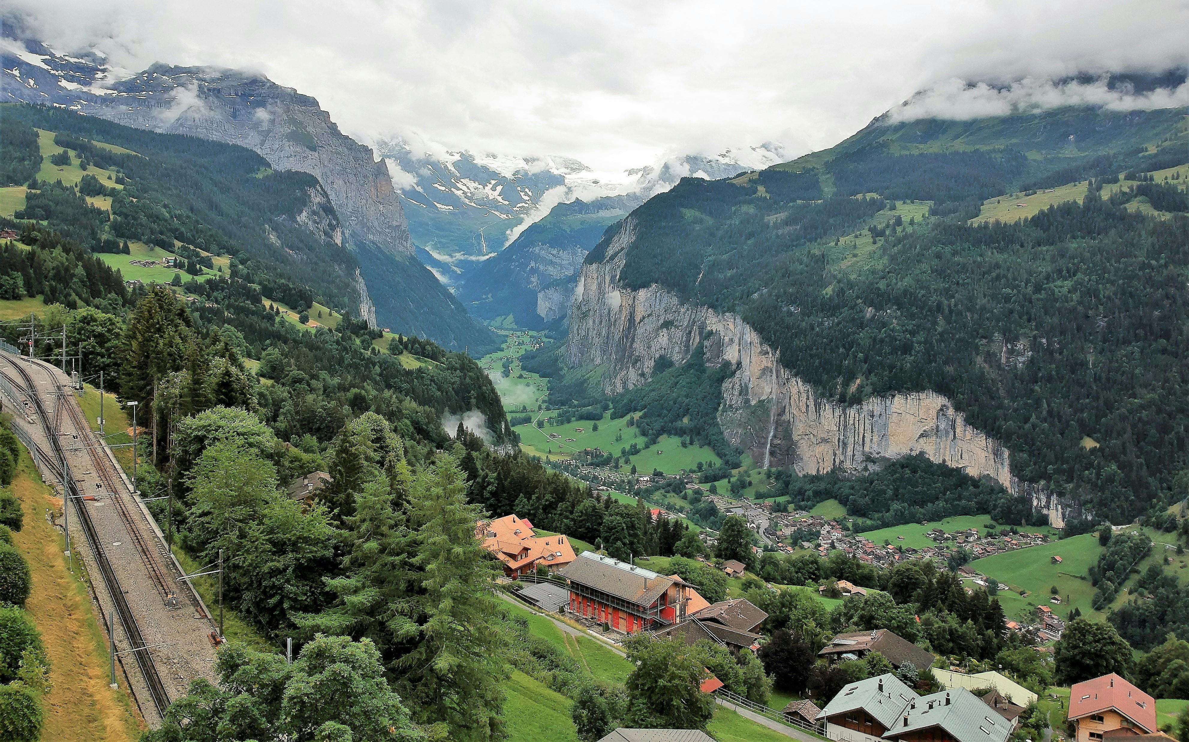 A sweeping alpine landscape with lush green trees and mountain slopes