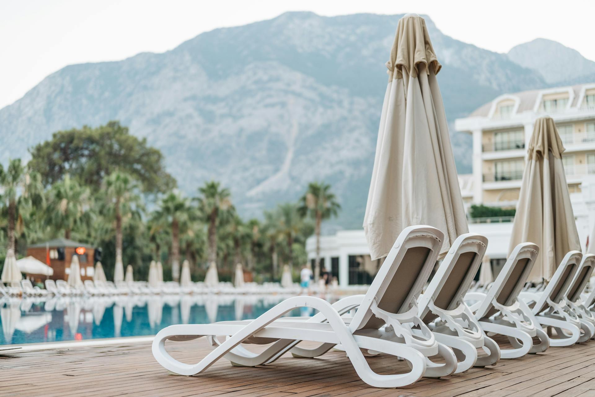 Lounge chairs and beach umbrellas on wooden deck by a pool