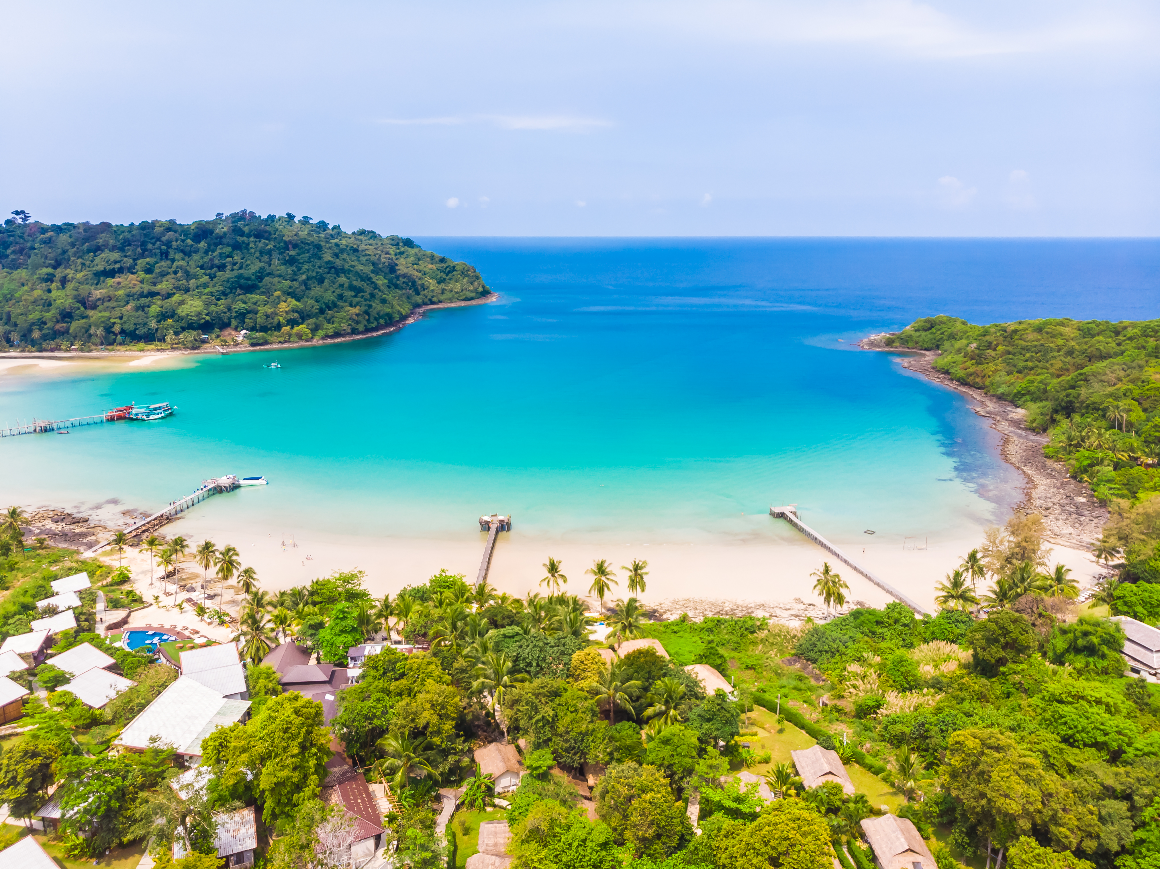 A tropical beach in Vanuatu with clear turquoise waters, soft white sand and lush greenery