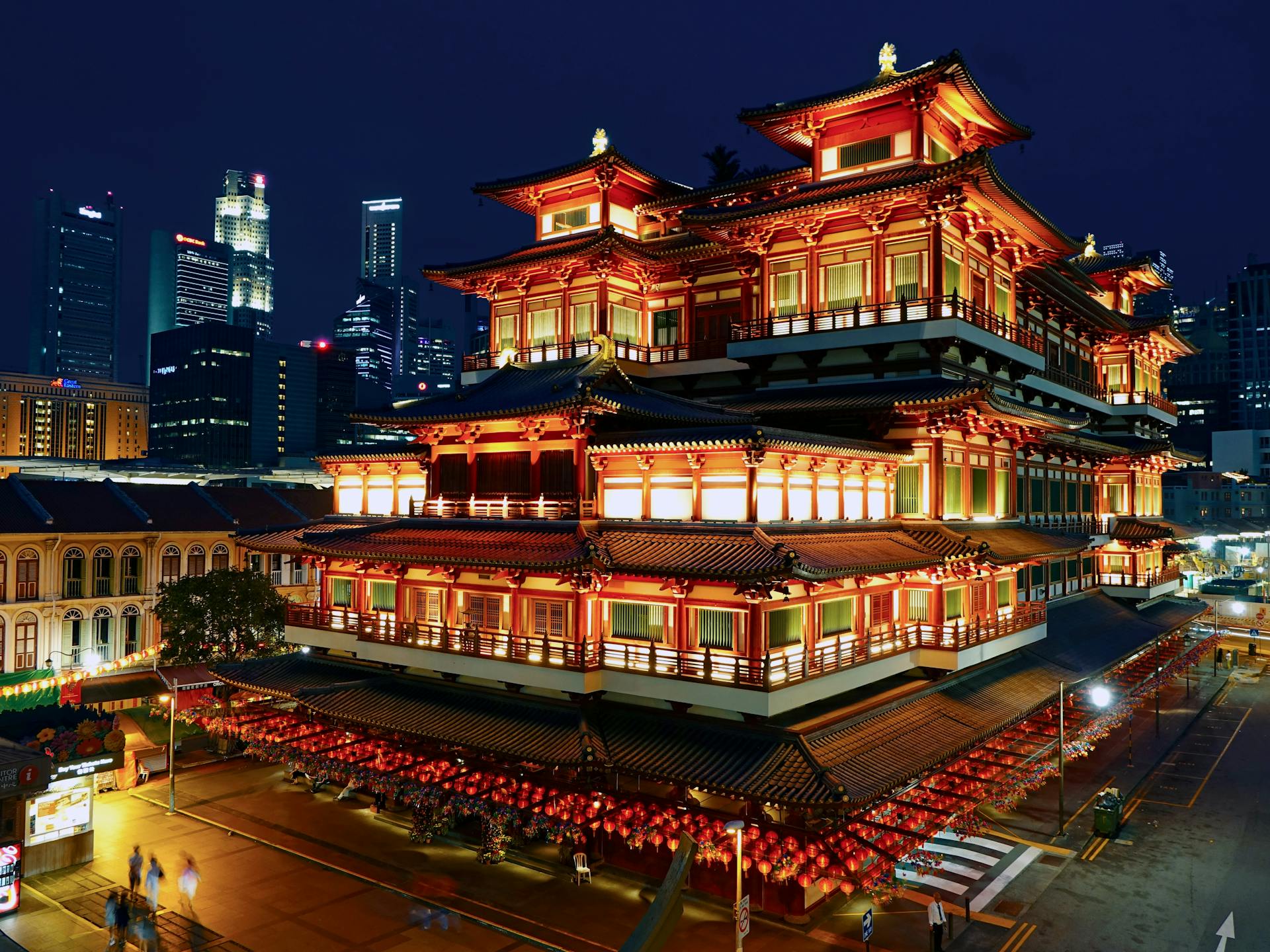 an illuminated red temple on the street in between several other buildings