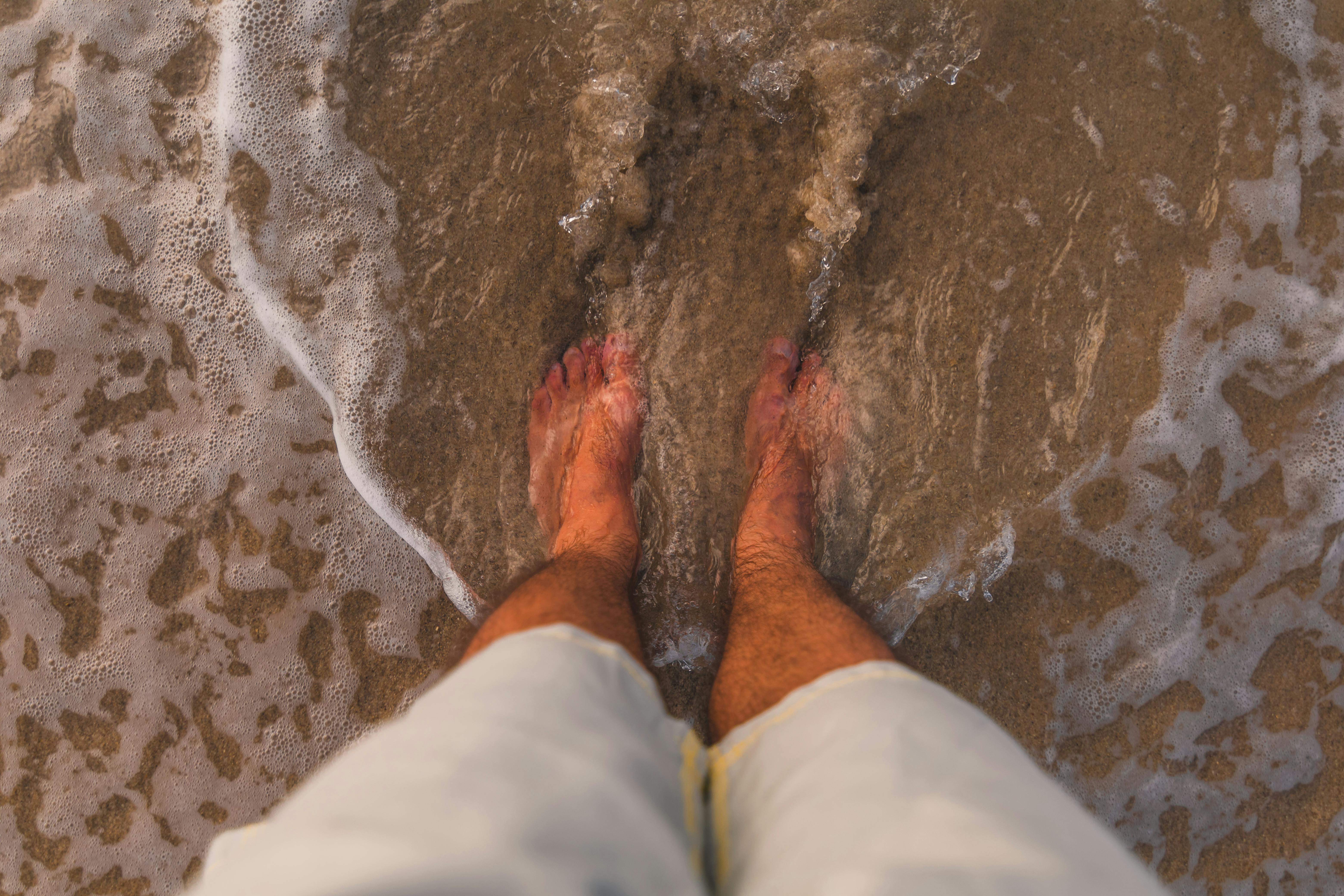 A person’s feet dipped in beach water
