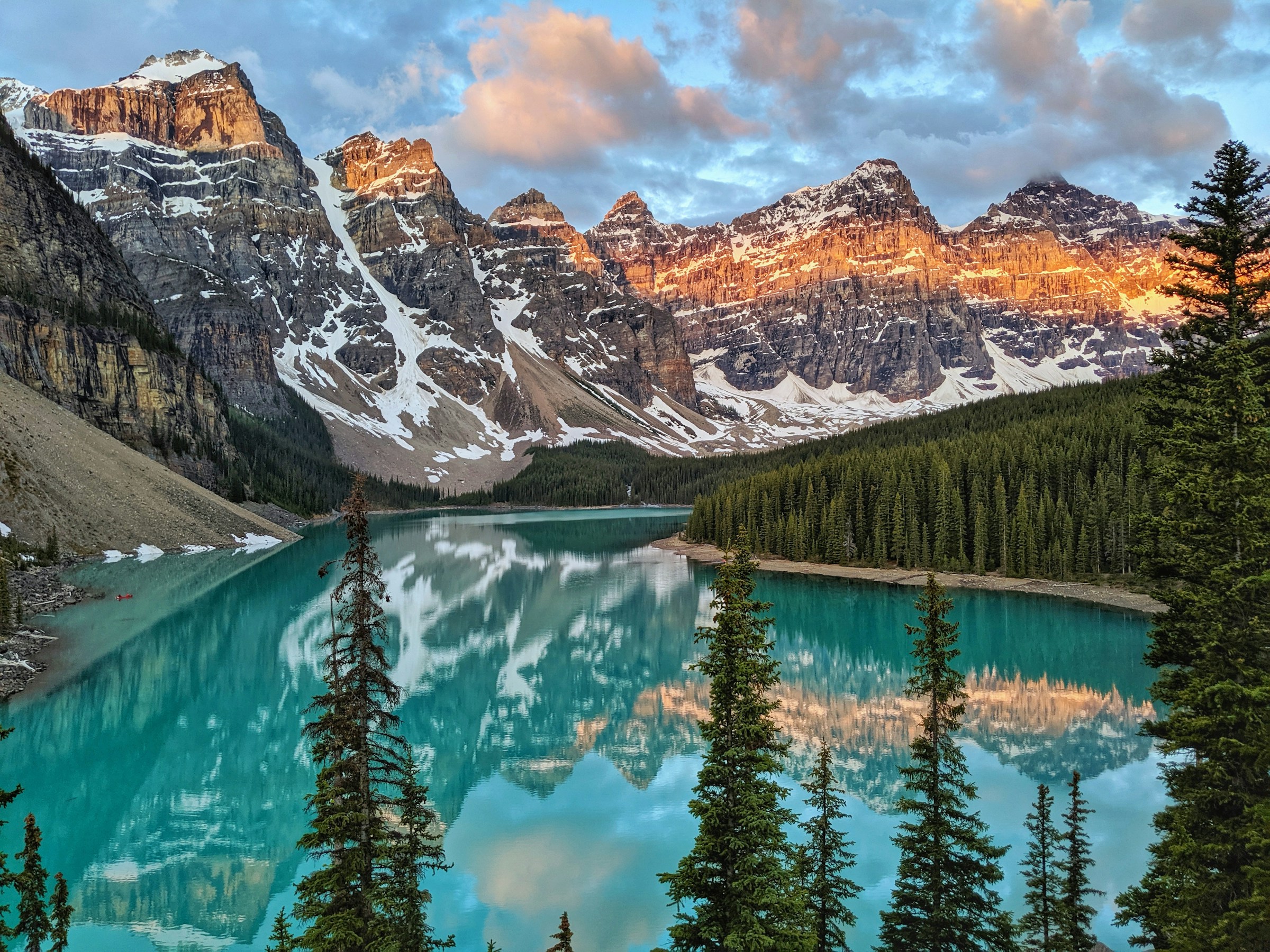 A lake in between mountains and pine trees
