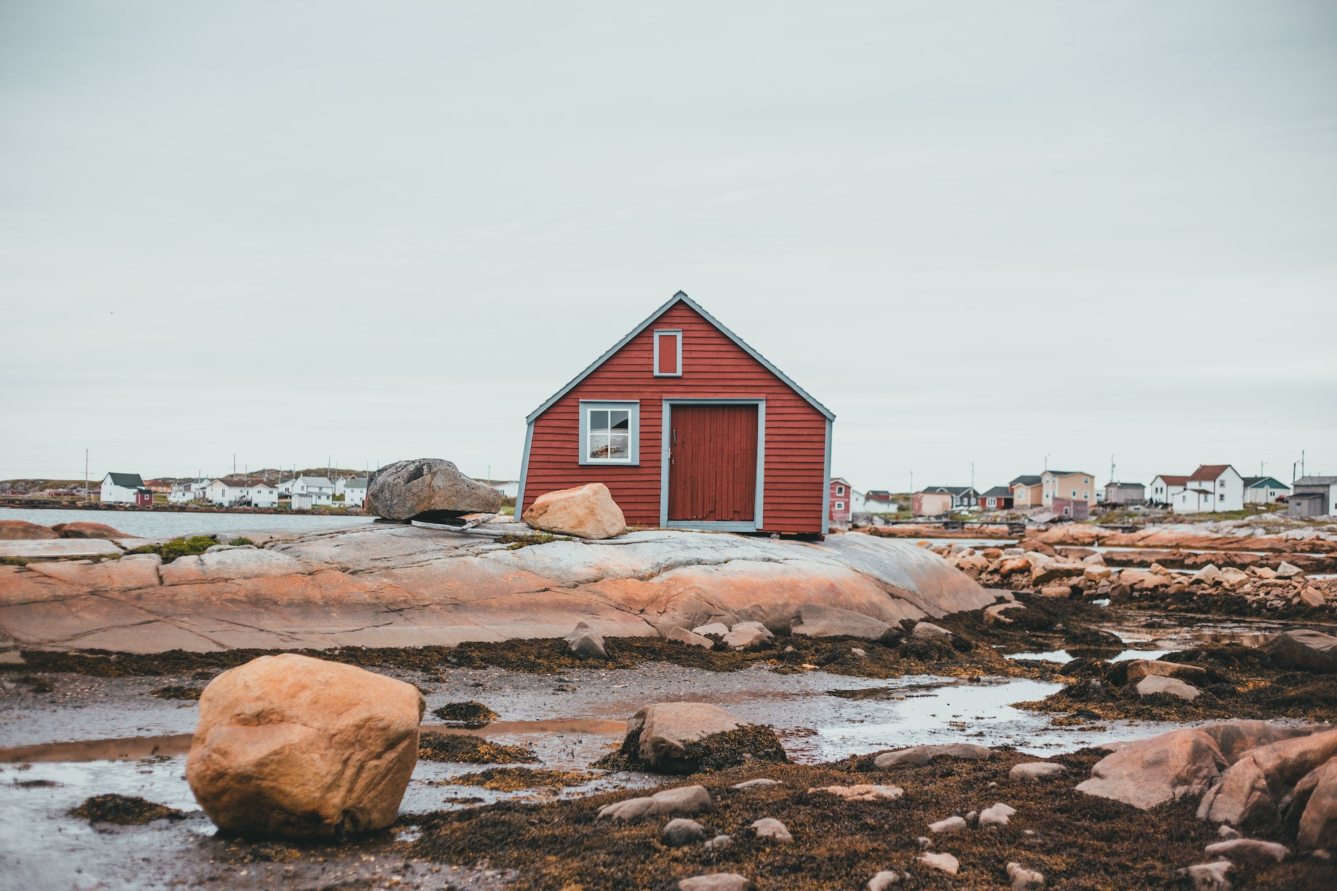 A red house in the middle of a rocky beach