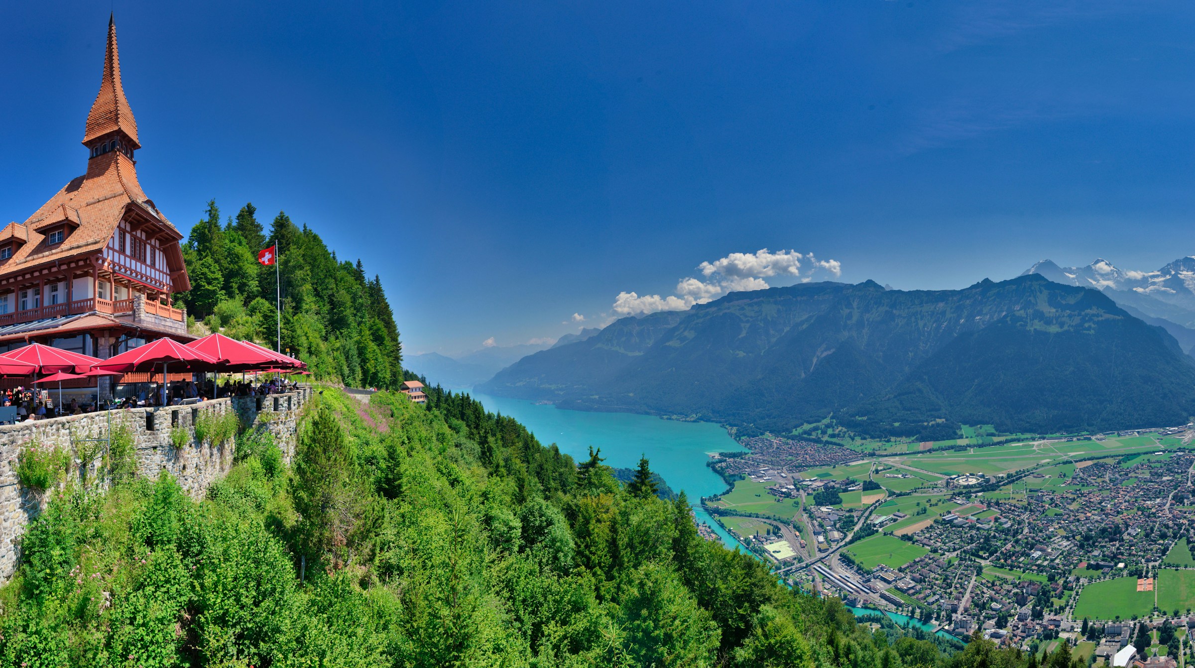 A view of a plateau with a building atop overlooking a lake and a town