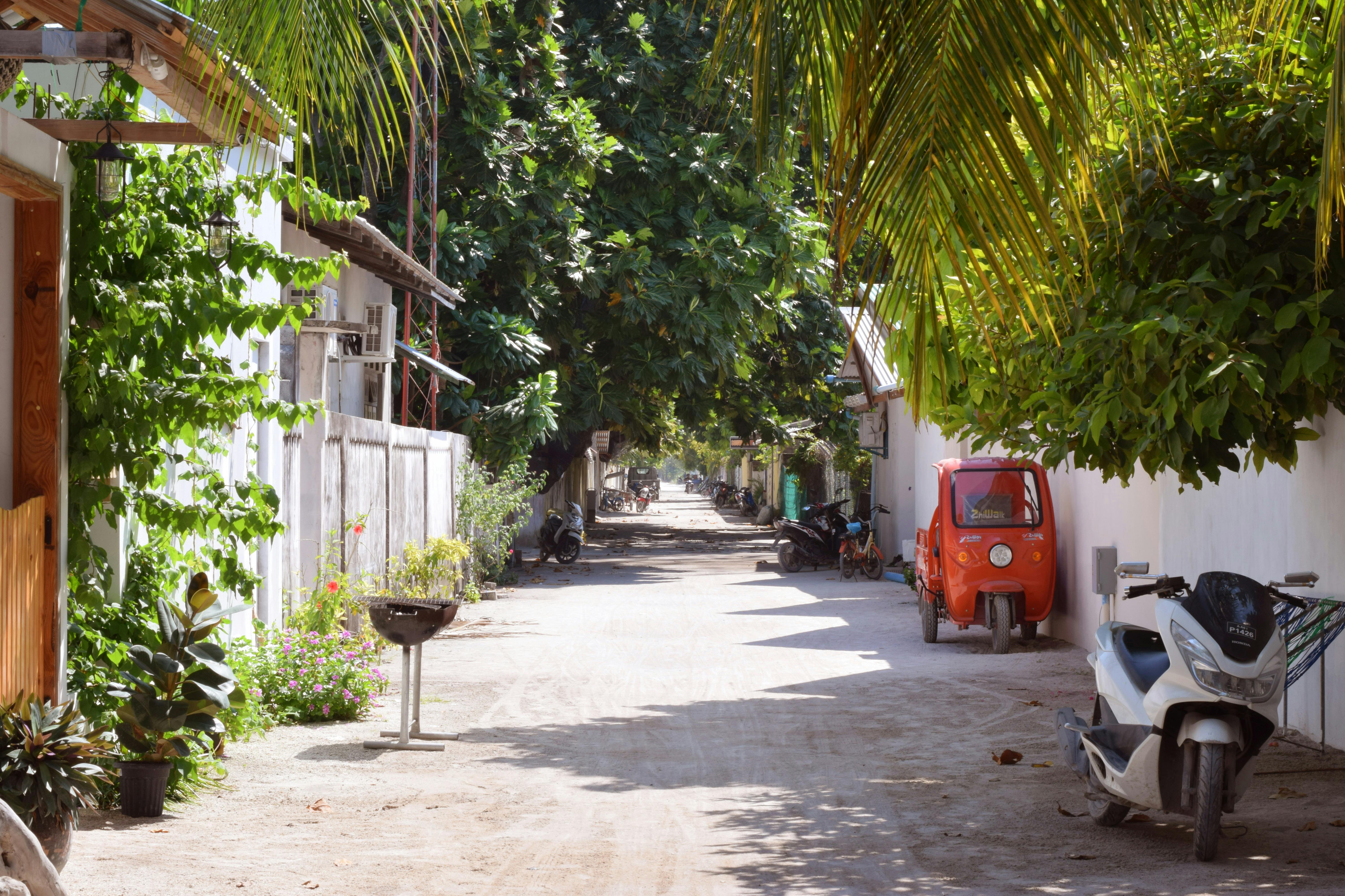 A row of parked motorbikes lines a sandy street on a Maldivian local island