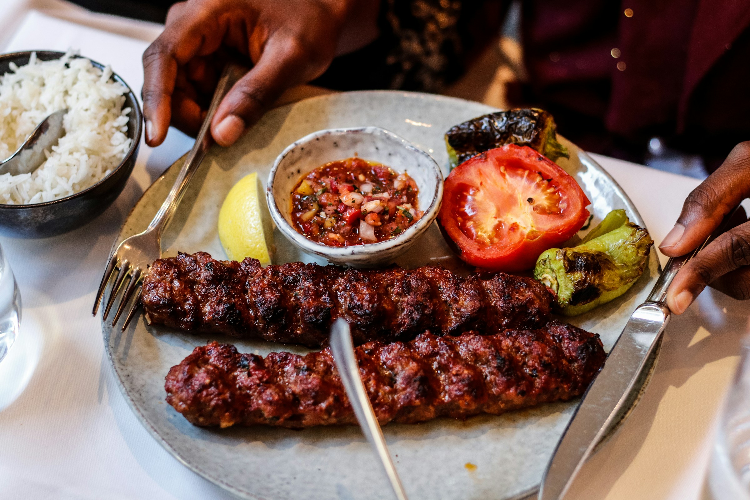 Juicy, perfectly charred Adana kebabs served with grilled vegetables and a side of rice.