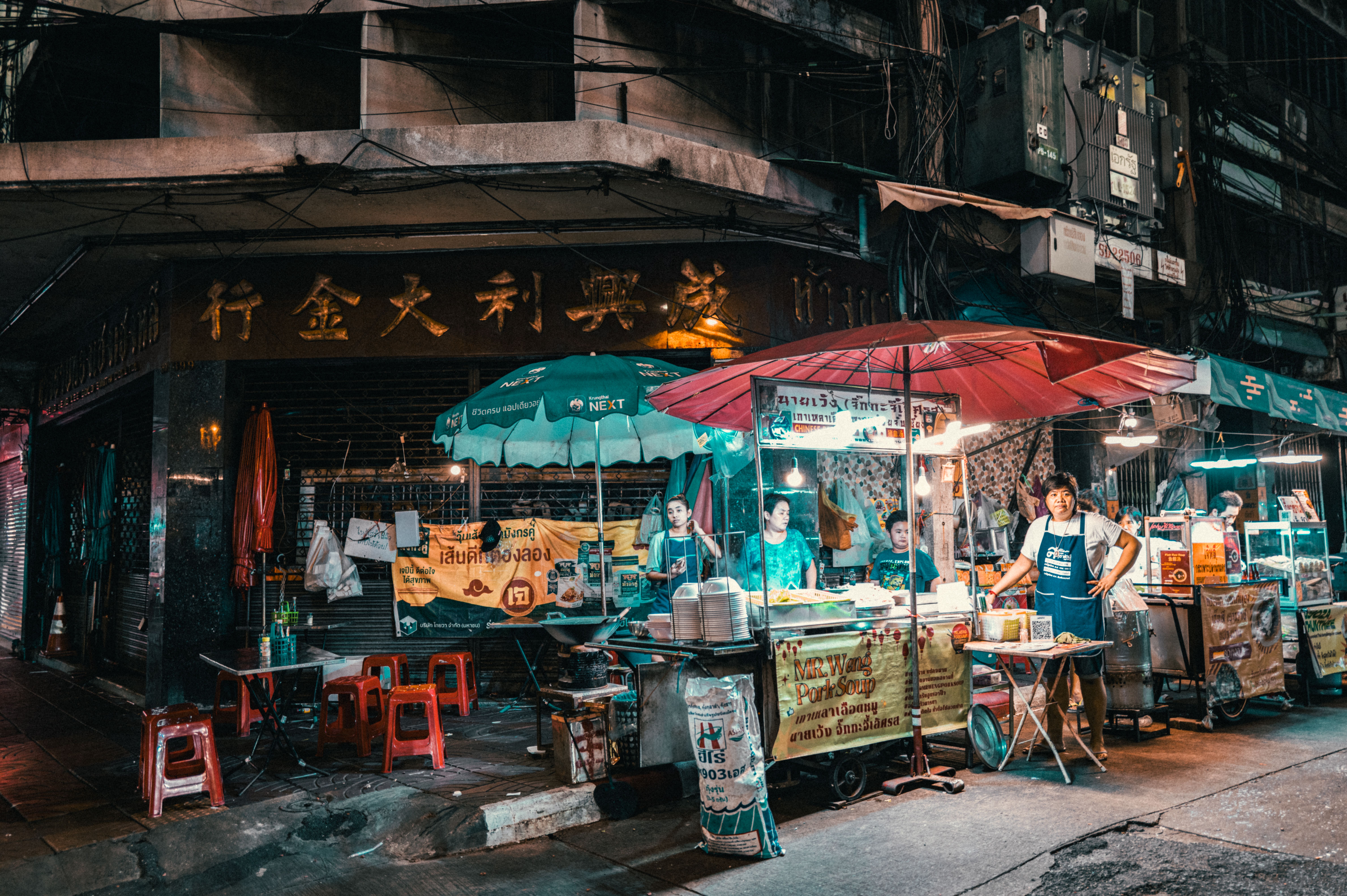 A vibrant Thai street food stall comes alive with sizzling woks